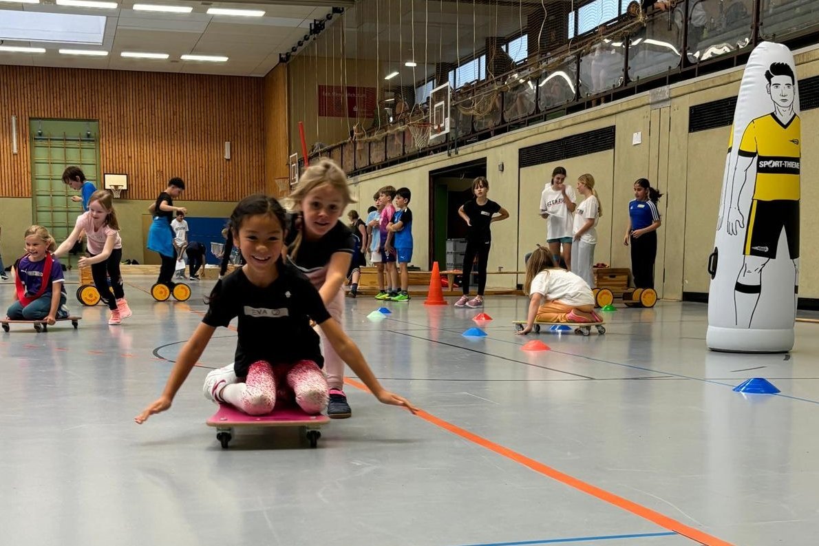 Kinder auf Rollbrett in der Turnhalle