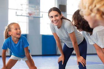 Junge Frau lächelt im Kreis mit Kindern
