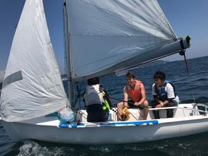 Zeigt drei Jugendliche beim Segeln auf einem kleinem Segelboot